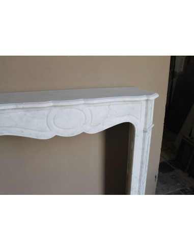Caminetto antico Pompadour scolpito in marmo bianco dalle linee iconiche, d'un barocco leggero.
