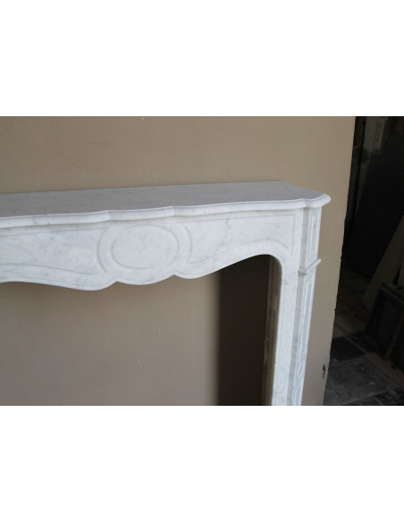 Caminetto antico Pompadour scolpito in marmo bianco dalle linee iconiche, d'un barocco leggero.