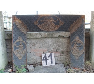 Controcuore antico in ghisa d'arte con decori di putti e fondo d'elegante tapisserie floreale.