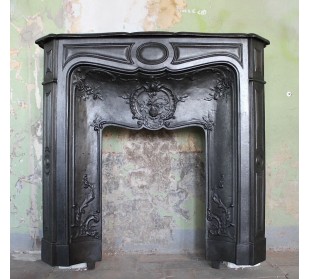 Caminetto antico Larcher in ghisa artistica con decori floreali. Al centro sta un "grenade", ovvero un melograno.