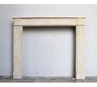 Cornice antica da camino di stile neoclassico scolpita in pietra beige chiara.