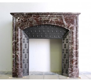 Camino antico in marmo rosso Levanto, provvisto di controcuore d'origine in ghisa artistica.